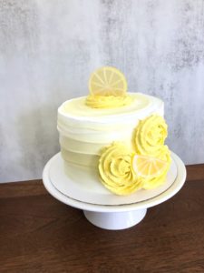 Fake Cake: fake lemon cake frosted in white with faux lemon slices and yellow rossettes.